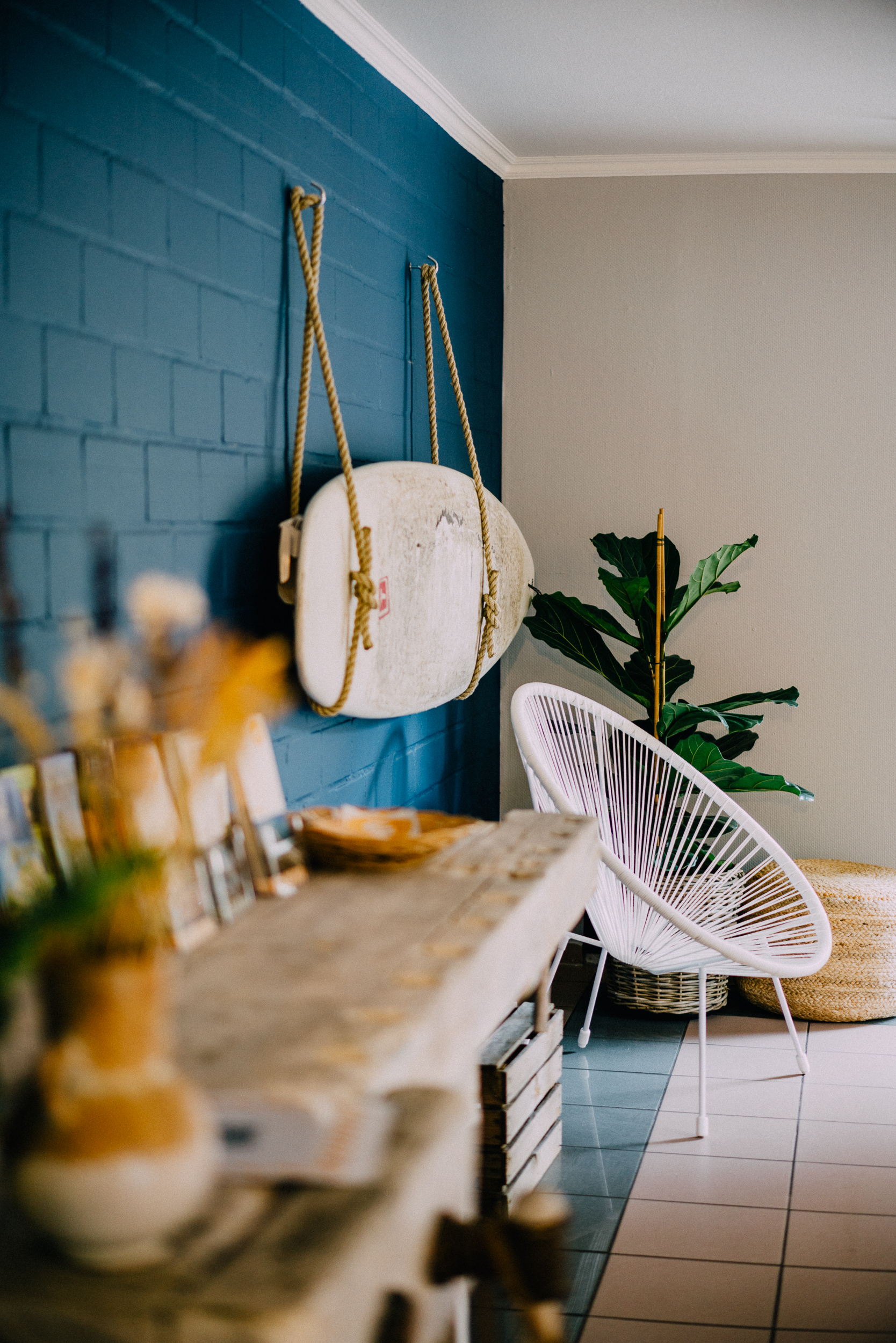 Ein moderner Raum mit einem weißen Stuhl, einer Topfpflanze, einer blauen Wand und rustikalen Deko-Akzenten.